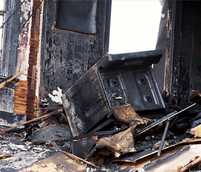 a fire damaged kitchen with soot covering everything and debris everywhere