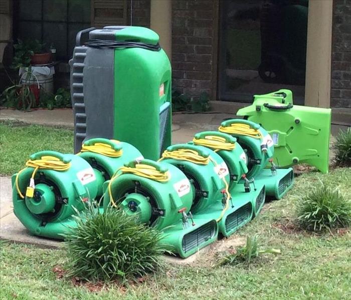 SERVPRO drying equipment on the patio of a porch. 