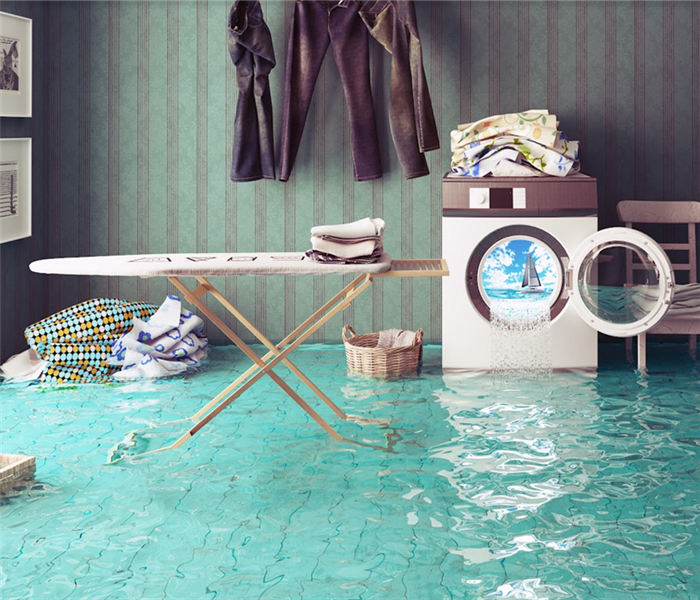 a flooded laundry room with water spilling from the washer and onto the floor